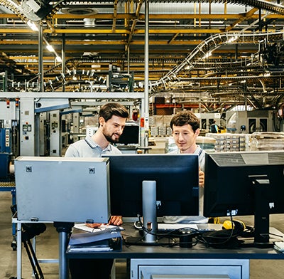 Two men at computers at a manufacturing plant