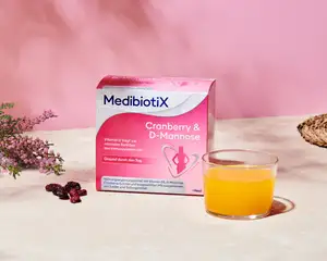 Rosa Medibiotix Cranberry D-Mannose Produktverpackung neben Cranberries.