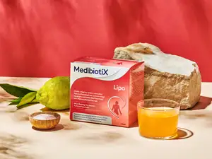 Rote Medibiotix Lipo Produktverpackung neben Glas und Zitrone.