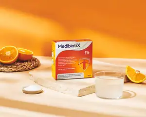 Orangene Medibiotix Fit Produktverpackung neben Glas und Orangenschnitzen.