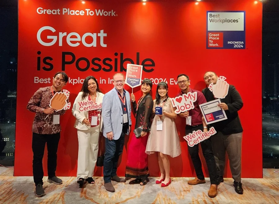 Indonesian team members in front of a red Great Place to Work banner