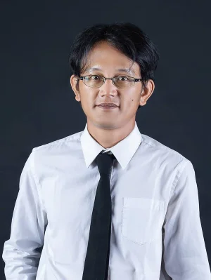 Indonesian man with glasses on, smiling on a black background