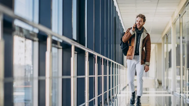 A man walking through Melbourne airport talking into a phone