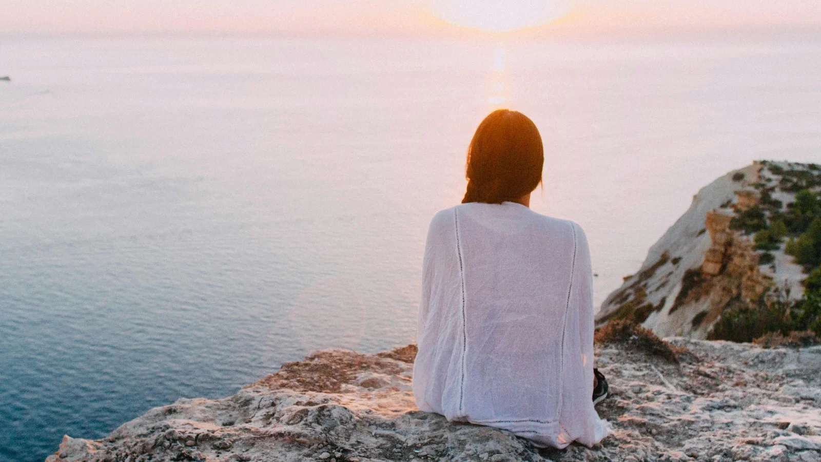 Woman sitting on a rock facing out to sea