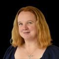 Headshot of Jess Goode, standing against a black background