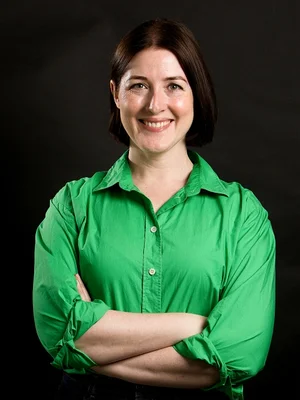 Picture of Luminary employee, Anna Potter smiling standing in front of a black screen in a green top