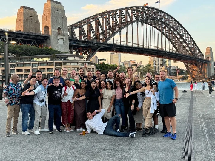 A large group of Luminary team members standing in front of Sydney Harbour Bridge at SXSW 2023