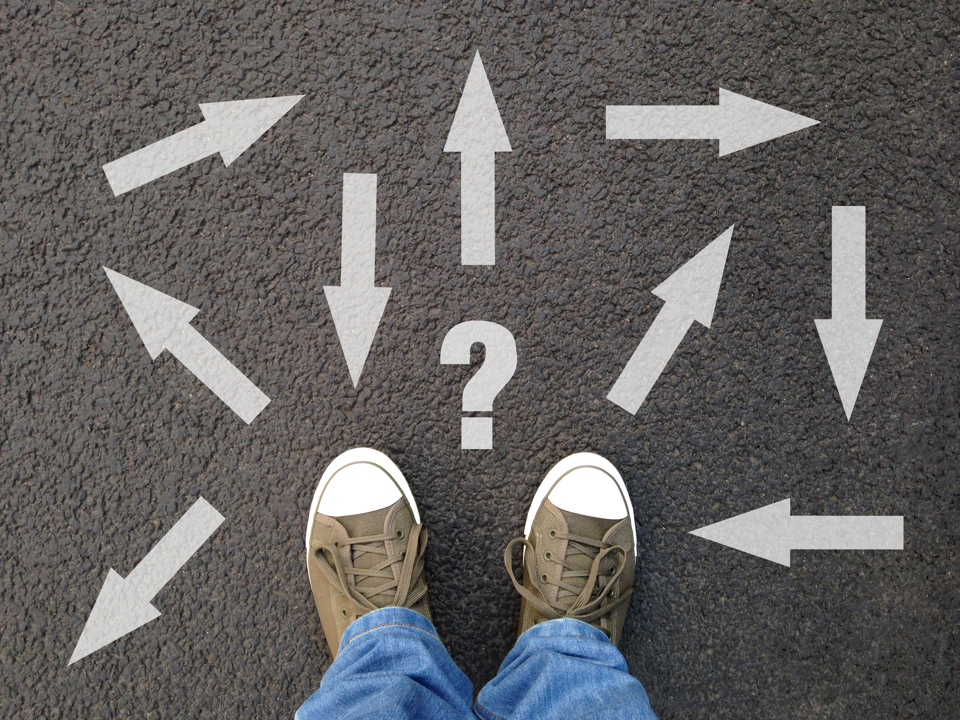 feet-standing-on-asphalt-with-multitude-of-arrows