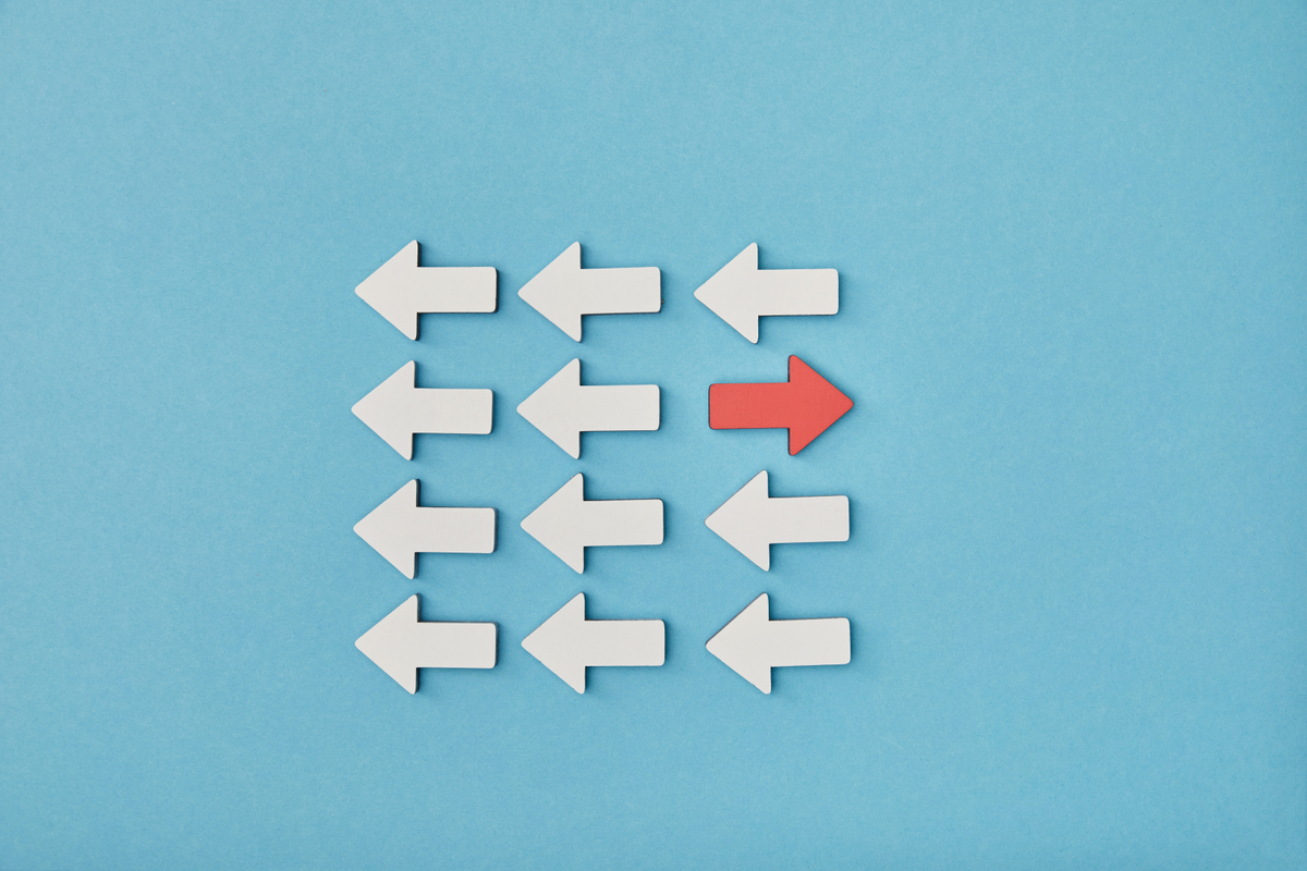 Arrows pointing one way with one red arrow going opposite direction