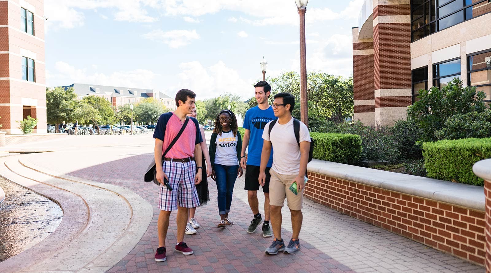Five Baylor students walking together outside on campus.