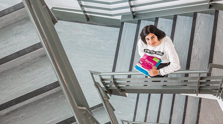 Student holding books on stairwell