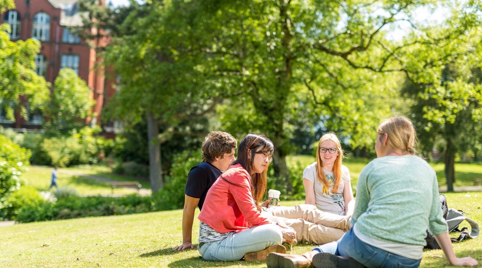 four students sitting in a park