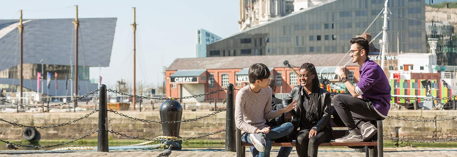 Three students sitting on a bench in Liverpool