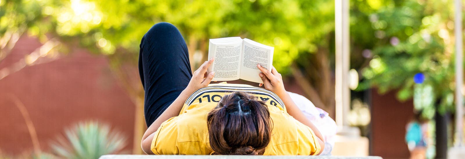 A student reading a book outside.