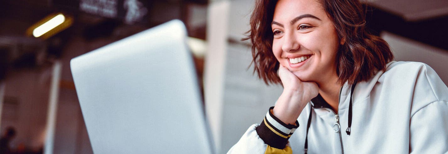 Student sitting and smiling at laptop