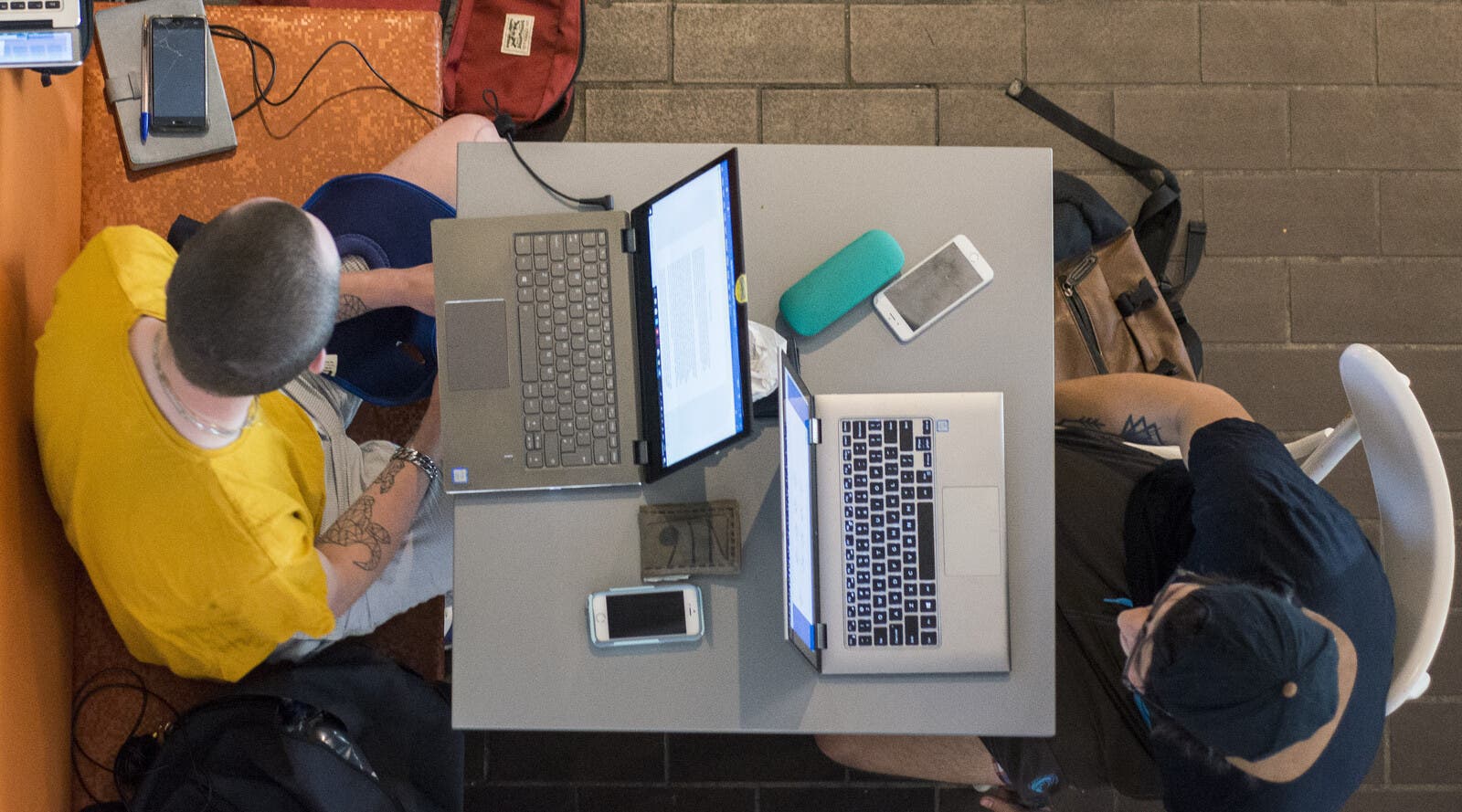 Students studying remotely on laptops in a cafe