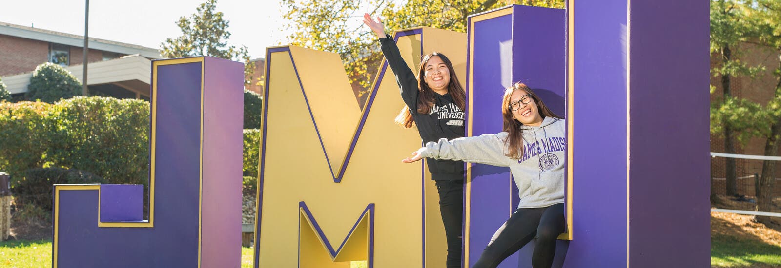 Two students posing with JMU sign