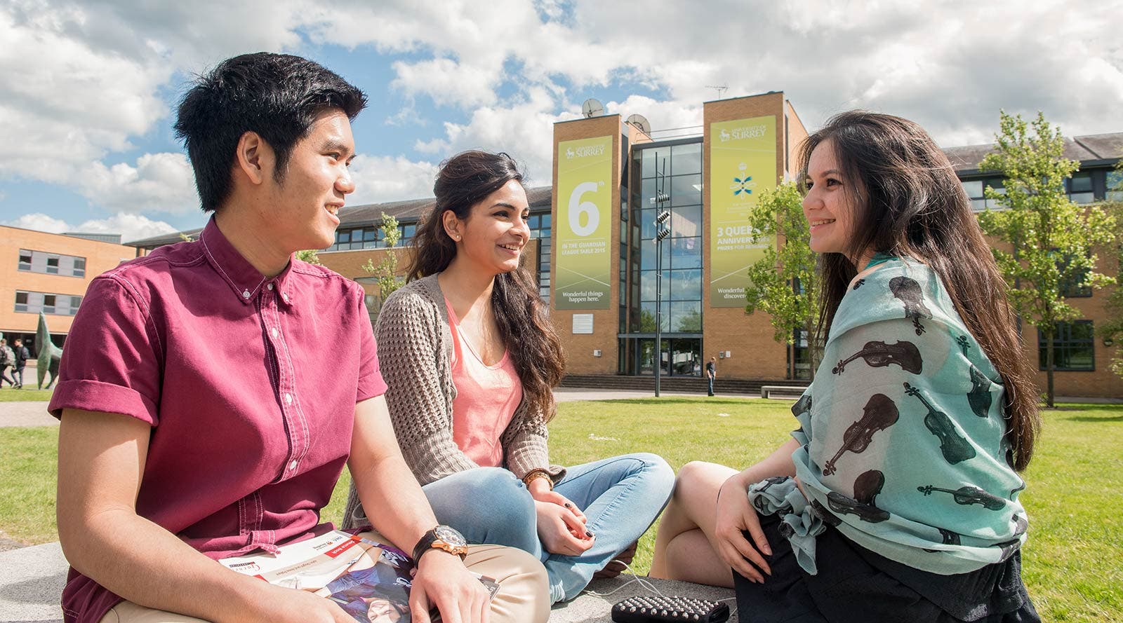 Surrey students sitting on grass outside campus