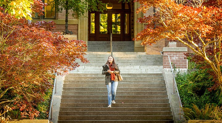 Student walking down steps holding laptop