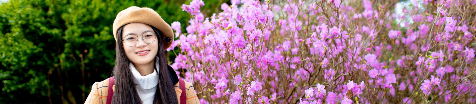A student smiling in front of blossoms