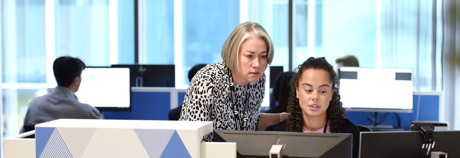 A tutor assisting a student at a computer