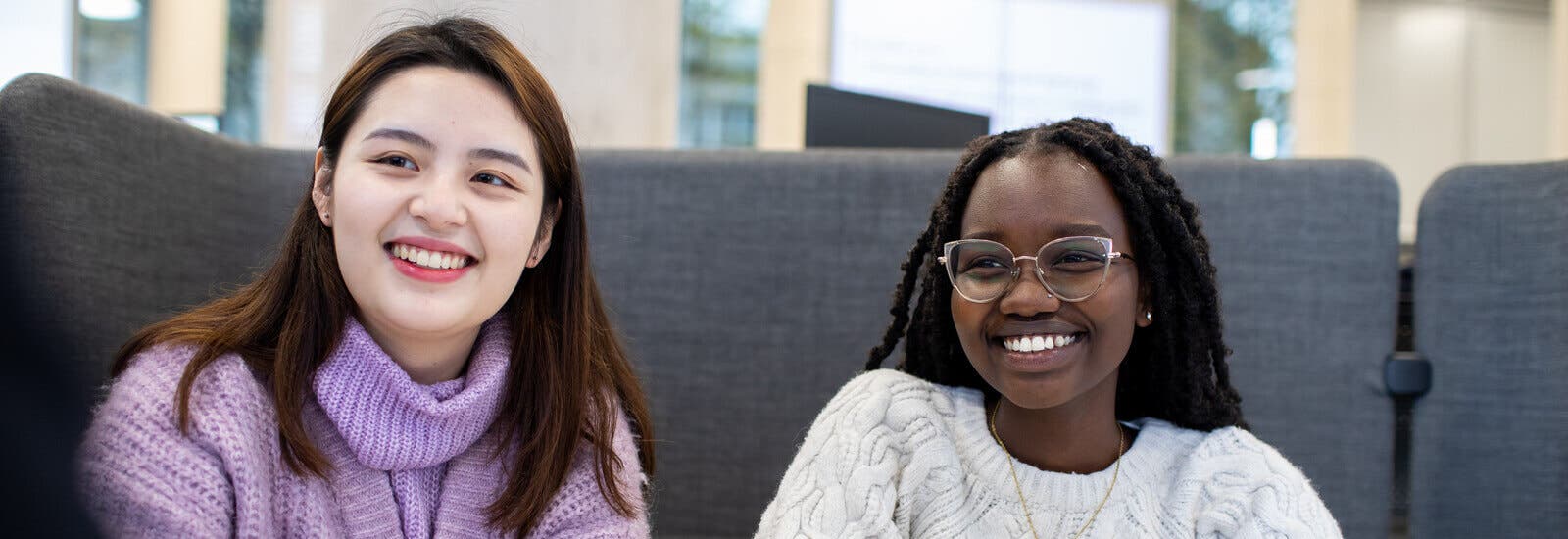 Students smiling and sitting in front of sofa