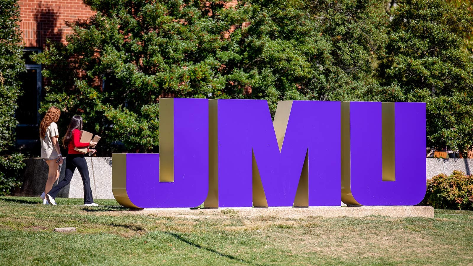 James Madison University students walking past a JMU statue