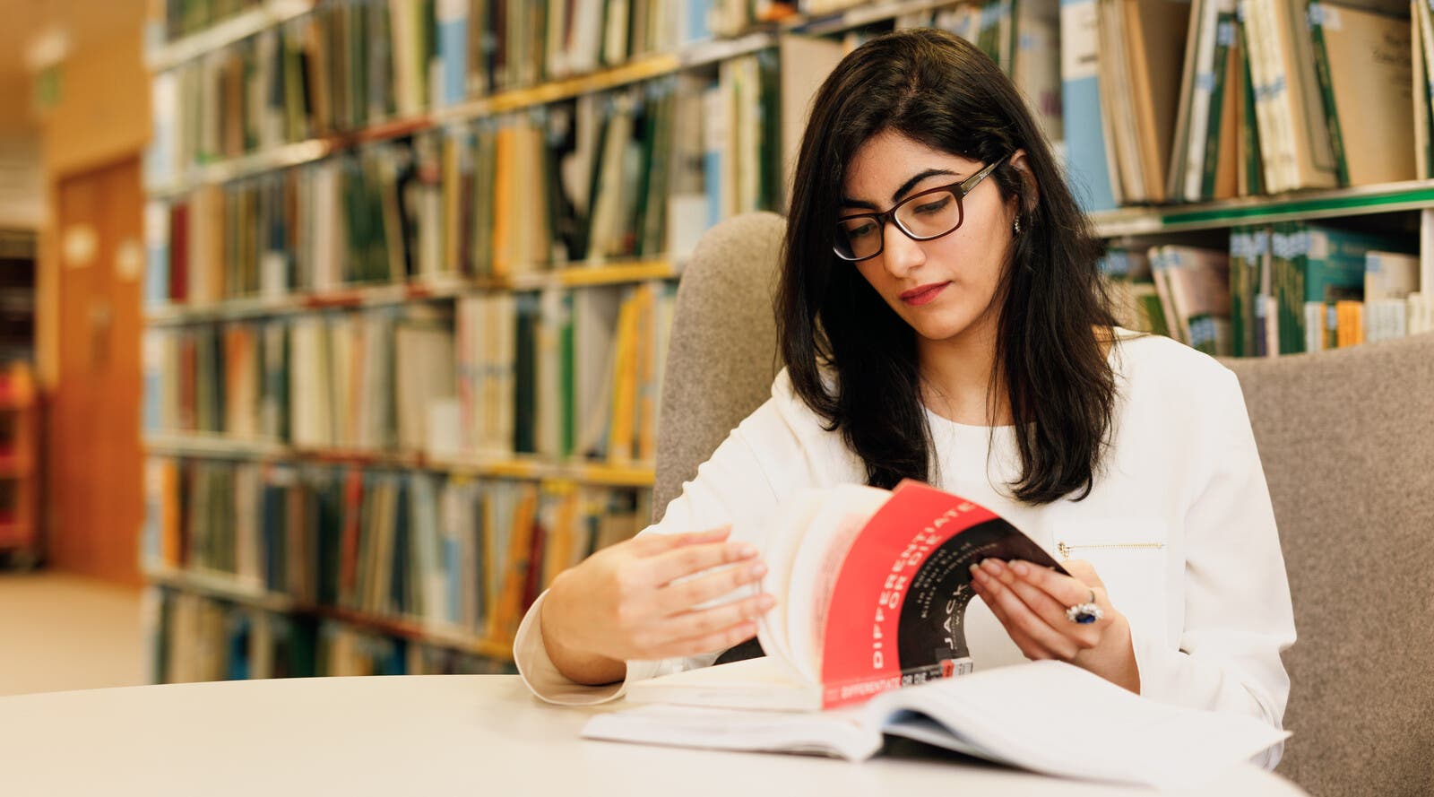 Student flipping through book in library