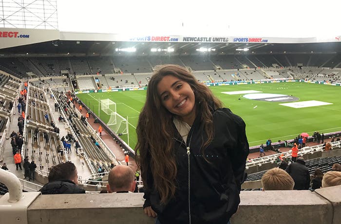Durham student smiling in front of football pitch