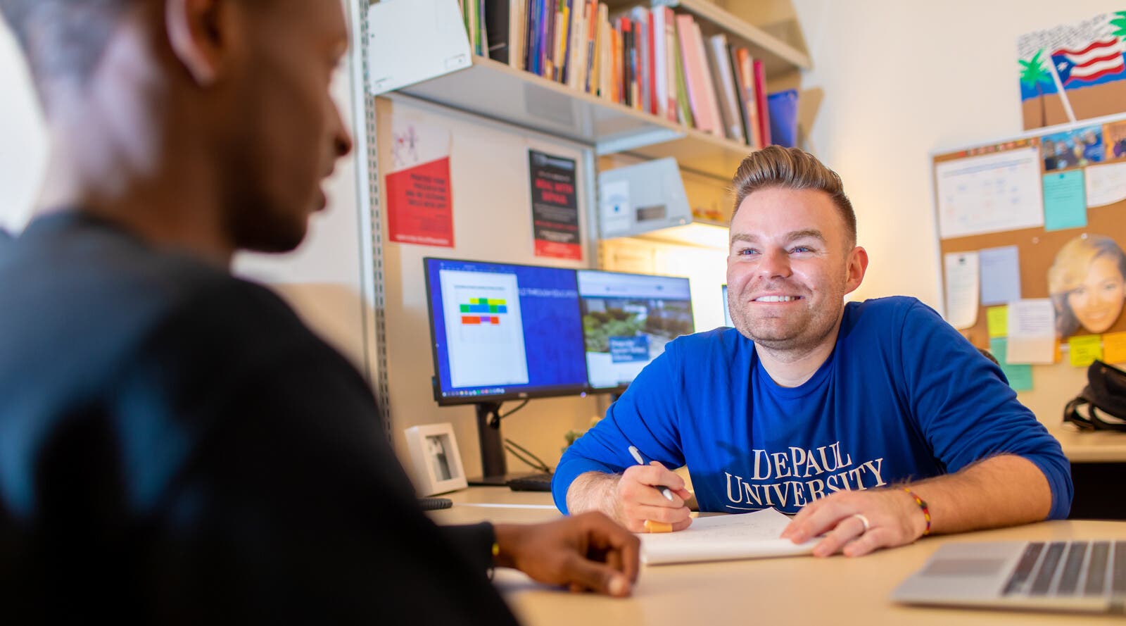 DePaul admissions assistant talking with student at desk