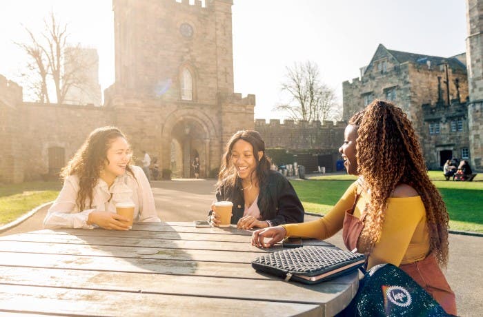Students sitting outside Durham castle and drinking coffee