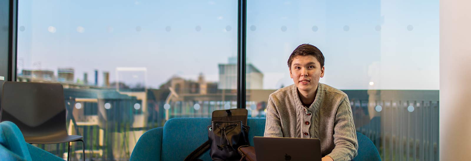 Student sitting on laptop in front of window