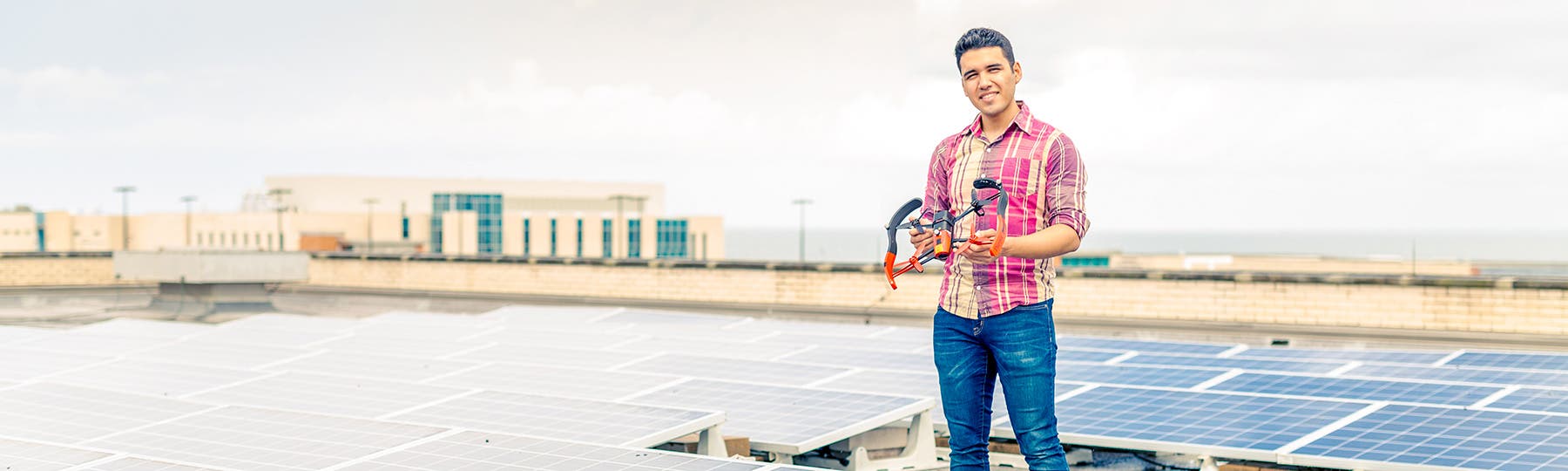 Student standing on rooftop holding drone
