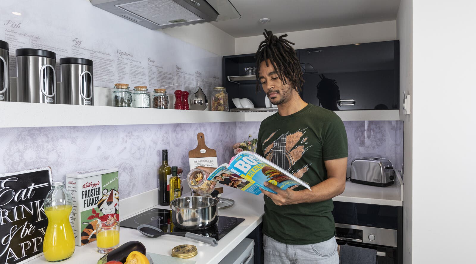 Student reading a magazine in accommodation kitchen