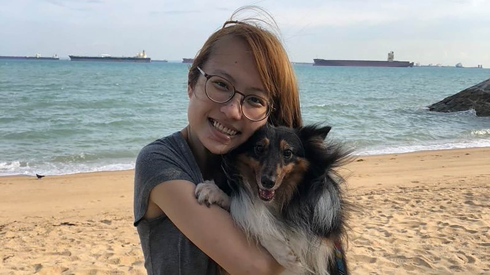 Tricia from Singapore holding dog on beach