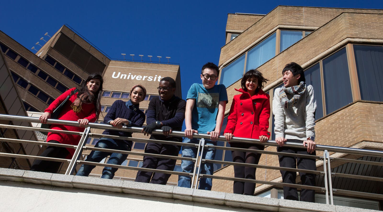 学生们在校园建筑前台阶上俯身微笑