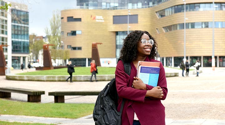 Student holding books outside campus