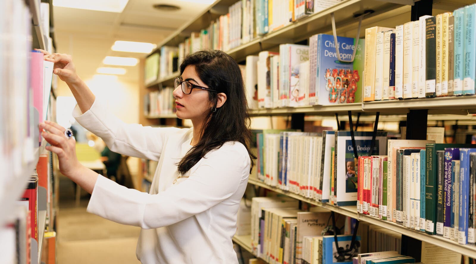 Student looking through bookshelf in library
