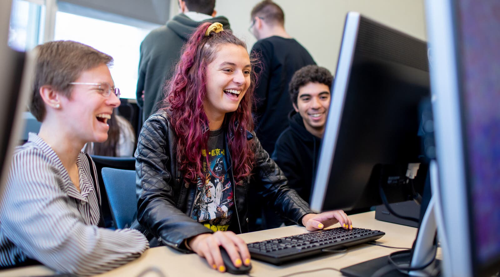 Students using computer and laughing