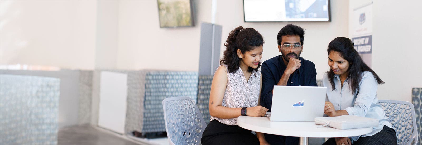 Three students working on a laptop