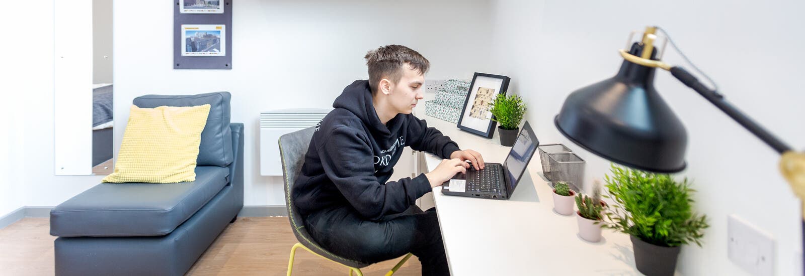 Student working on laptop at desk in accommodation