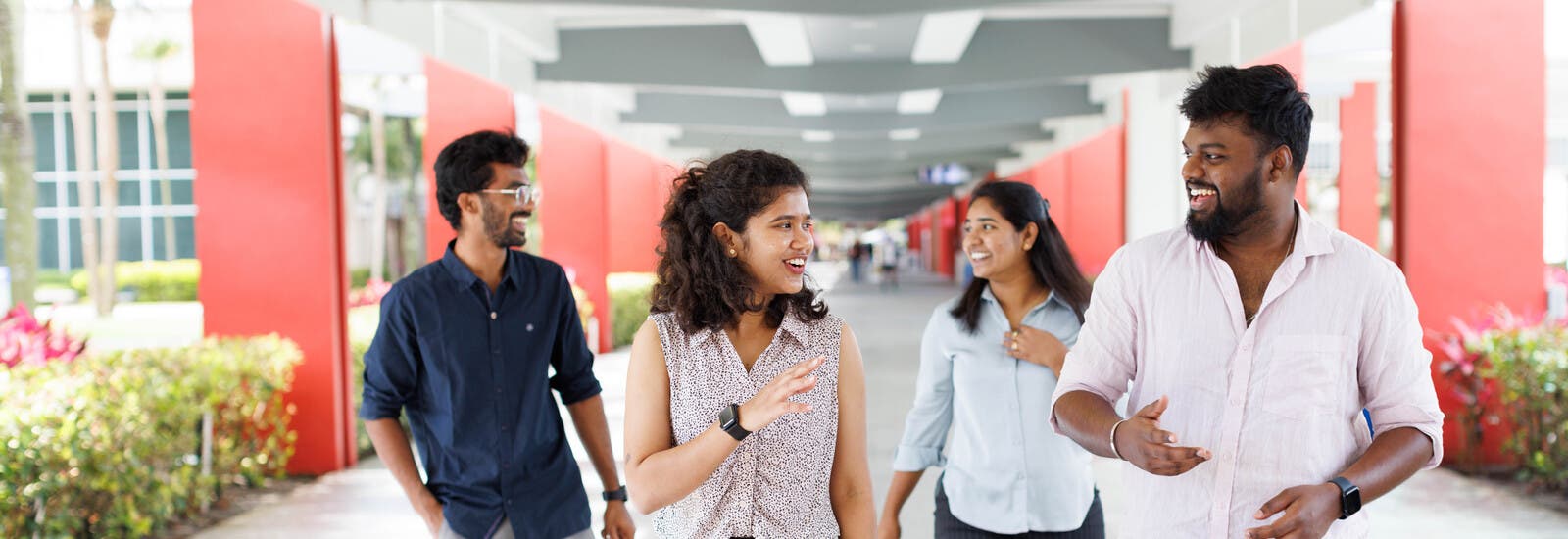 Four students walking down campus hallway