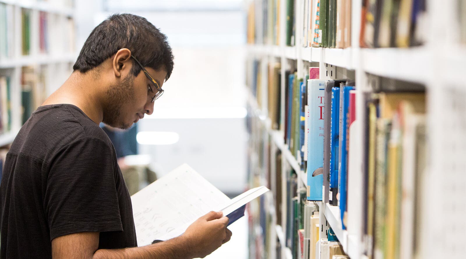 An international student reading a book in the library