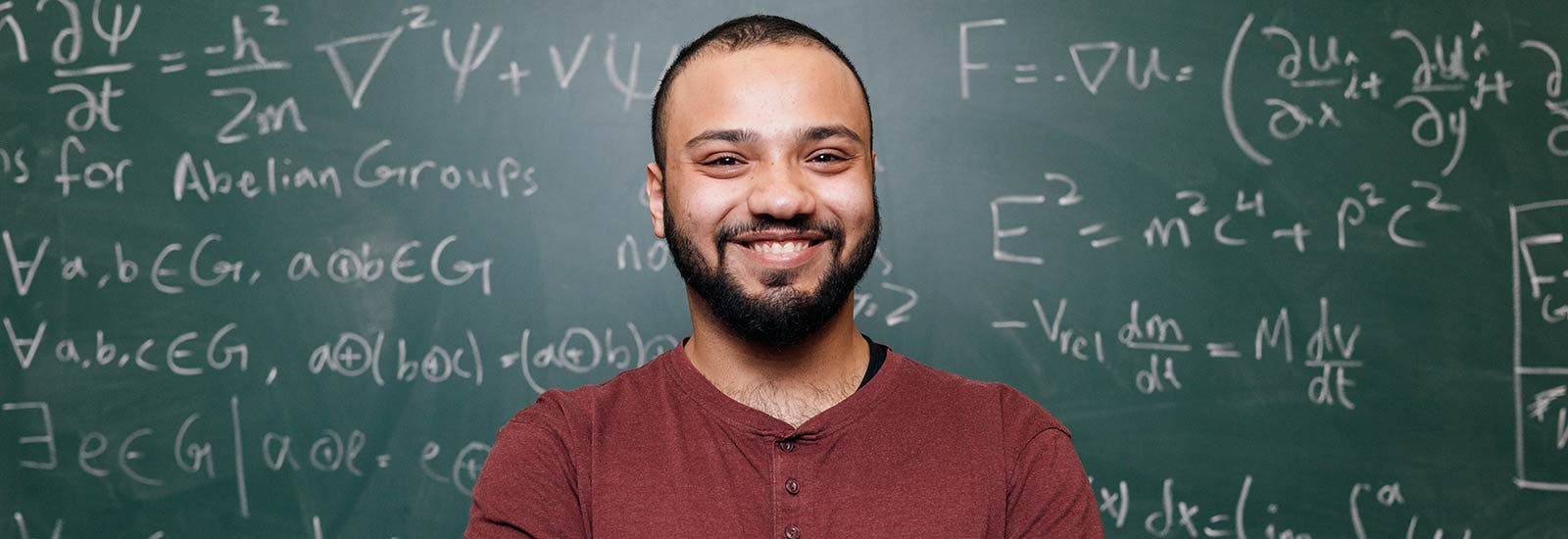 Surrey student smiling in front of blackboard