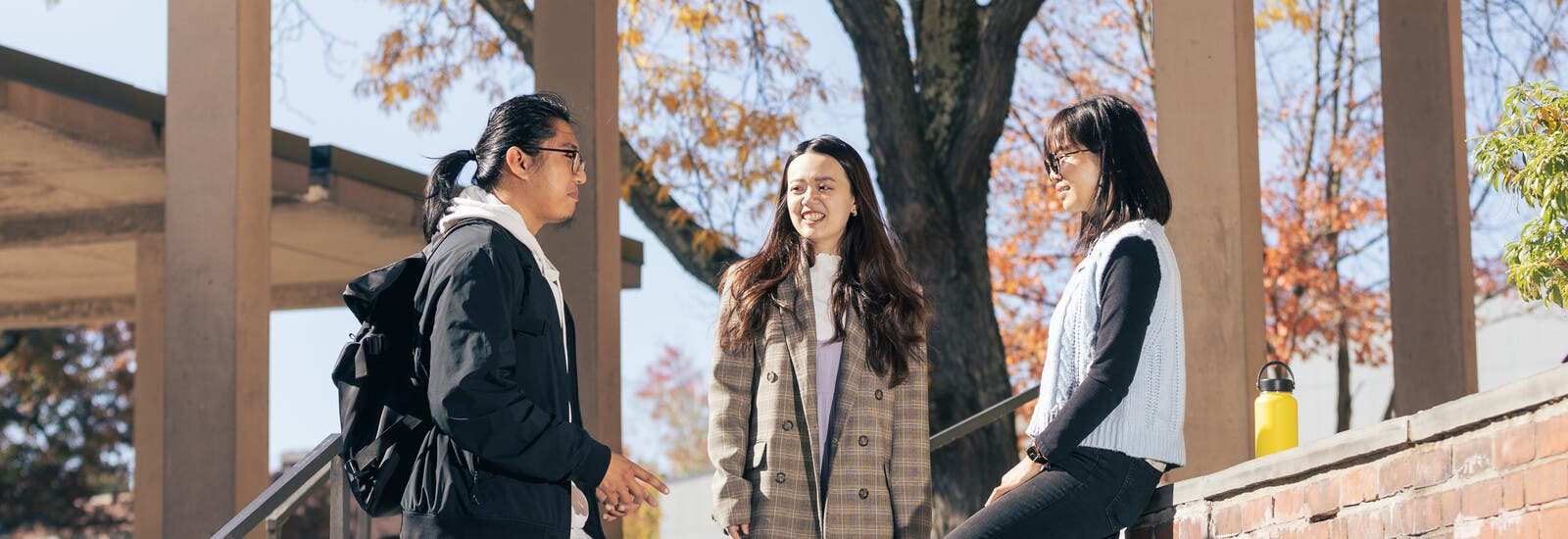 Three students talking outside on campus steps