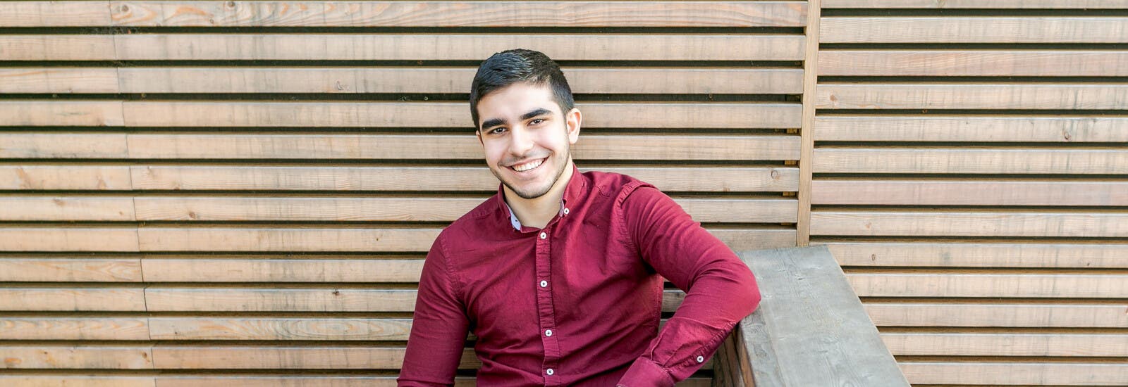 Student smiling and leaning against wall