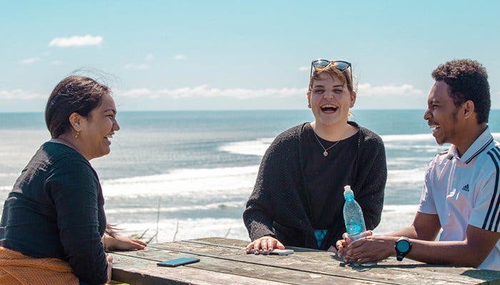 Students laughing together at table on beach