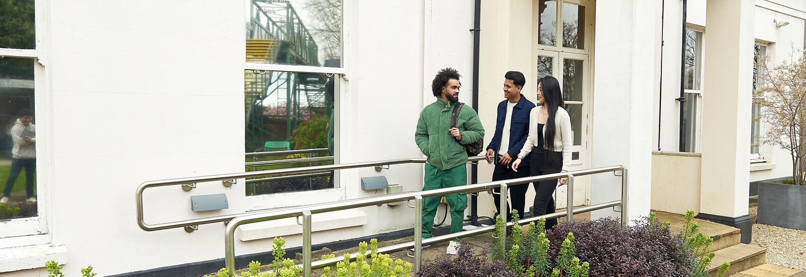 Three students walking out of a campus building