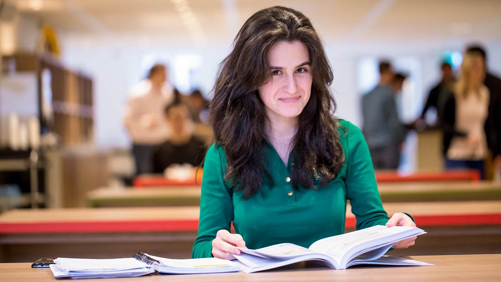 Student flipping through book and smiling at camera