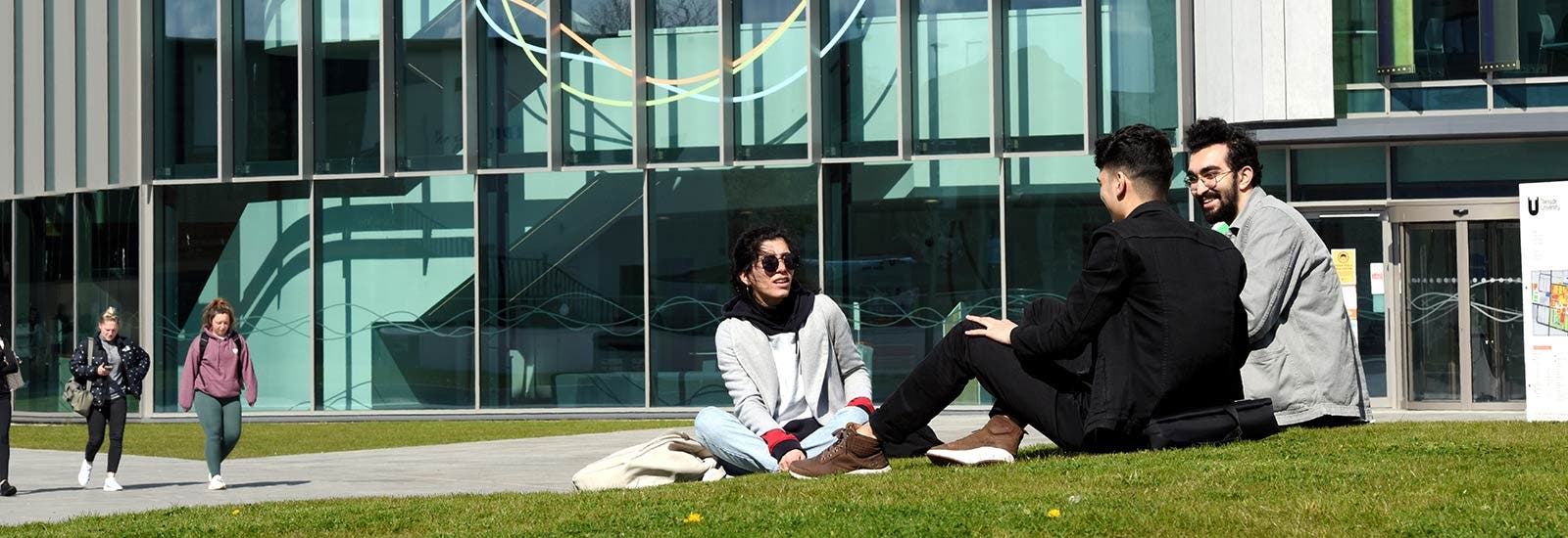 Students sitting on grass outside Teesside University campus